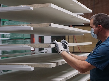 Empleado de Metrie colocando puertas imprimadas en estantes para que se sequen