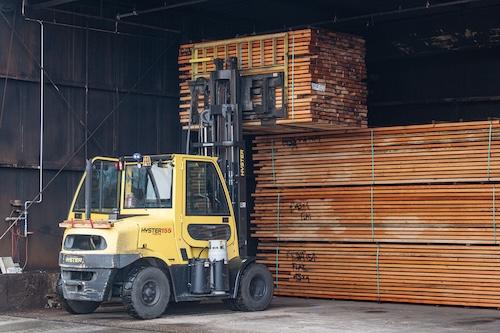 Forklift loading raw solid wood moulding into piled stacks